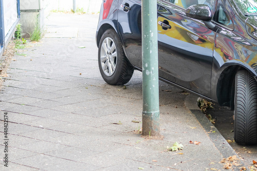 Badly parked car with tire on pavement shows wheel on walkway as traffic violation with penalty for poor driving and parking violation in urban streets with danger for pedestrians by selfish drivers