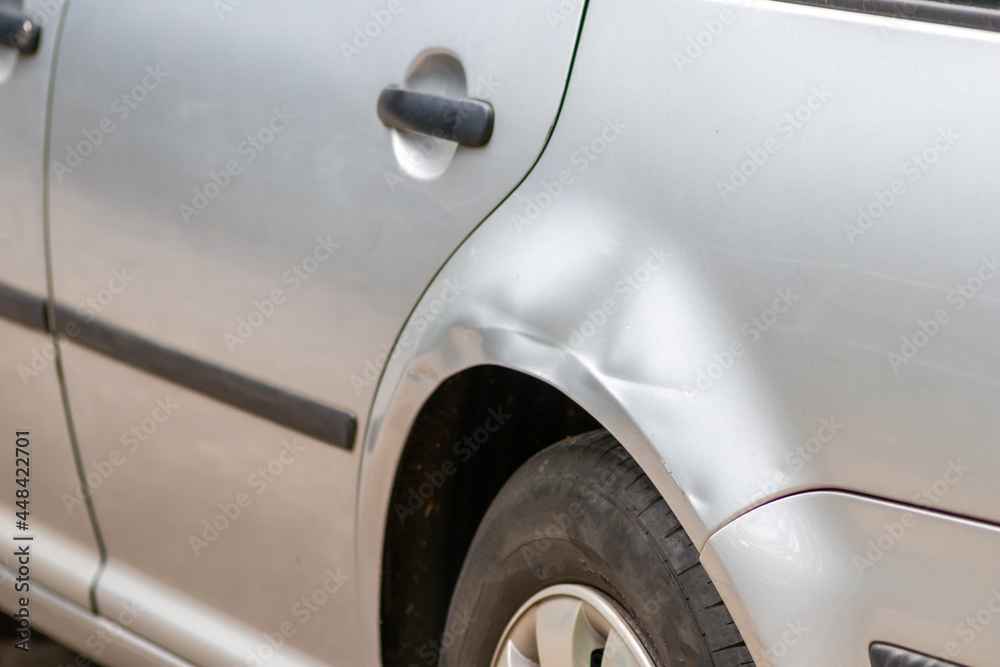 Dented car wing and fender with scratches and bumps after crash and car accident with hit-and-run driving and absconding shows need for car insurance and safety protection and mechanics garage service