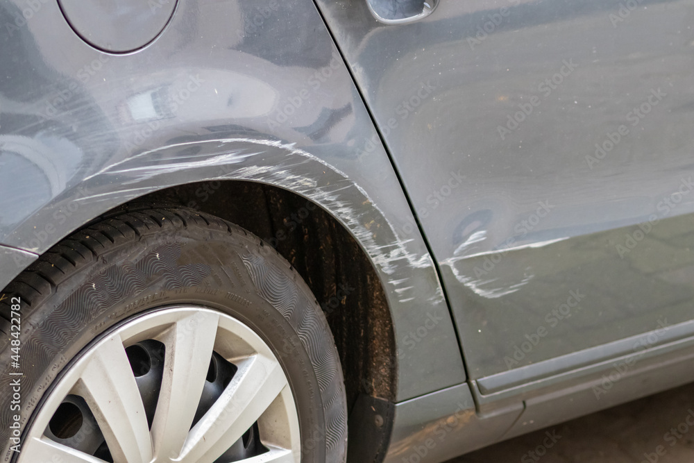 Dented car wing and fender with scratches and bumps after crash and car accident with hit-and-run driving and absconding shows need for car insurance and safety protection and mechanics garage service