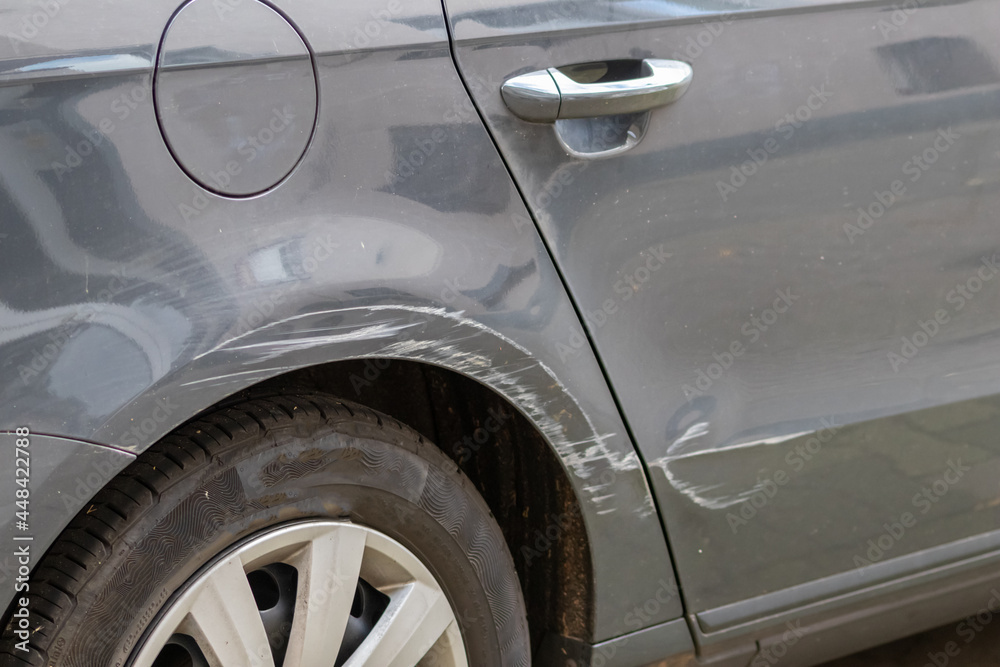 Dented car wing and fender with scratches and bumps after crash and car accident with hit-and-run driving and absconding shows need for car insurance and safety protection and mechanics garage service