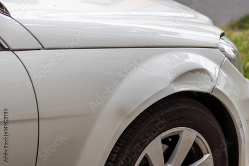 Dented car wing and fender with scratches and bumps after crash and car accident with hit-and-run driving and absconding shows need for car insurance and safety protection and mechanics garage service
