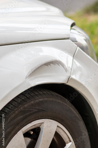 Dented car wing and fender with scratches and bumps after crash and car accident with hit-and-run driving and absconding shows need for car insurance and safety protection and mechanics garage service