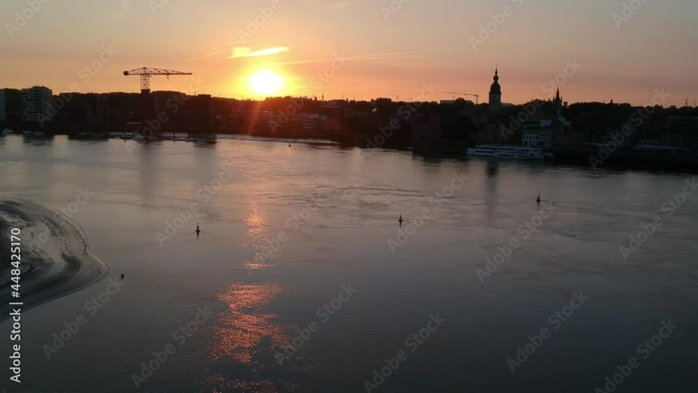 Golden sunset over silhouette of city with church tower and crane, aerial view
