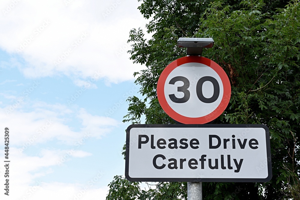 uk-road-sign-30mph-please-drive-carefully-blue-cloudy-sky-stock