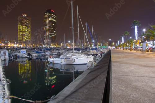 Night view of Port Olimpic harbor and marina in Olympic village(Vila Olimpica) in Barcelona. Mooring yachts, boats and other vessels sway at the pier. A summer vacation in Spain at Mediterranean sea. photo