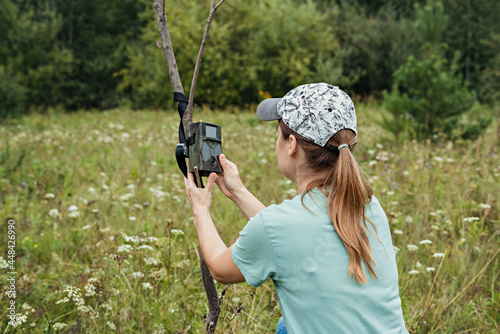 Fotografie Young woman scientist biologist zoologist sets camera trap for observing wild an