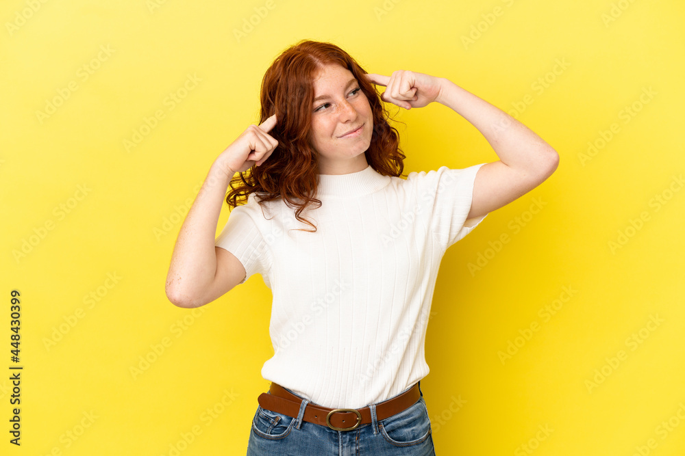 Teenager reddish woman isolated on yellow background having doubts and thinking Teenager reddish woman isolated on yellow background having doubts and thinking