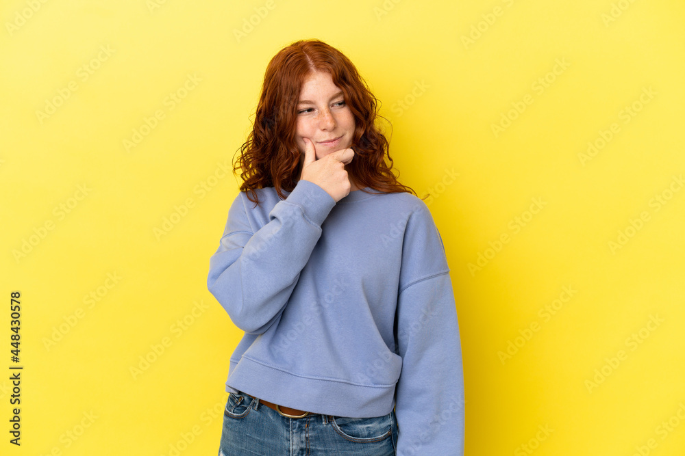 Teenager reddish woman isolated on yellow background thinking an idea while looking up Teenager reddish woman isolated on yellow background thinking an idea while looking up
