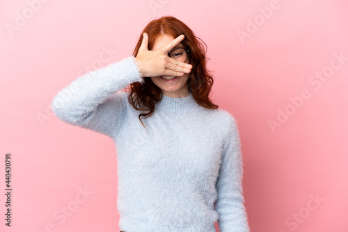 Teenager reddish woman isolated on pink background covering eyes by hands and smiling