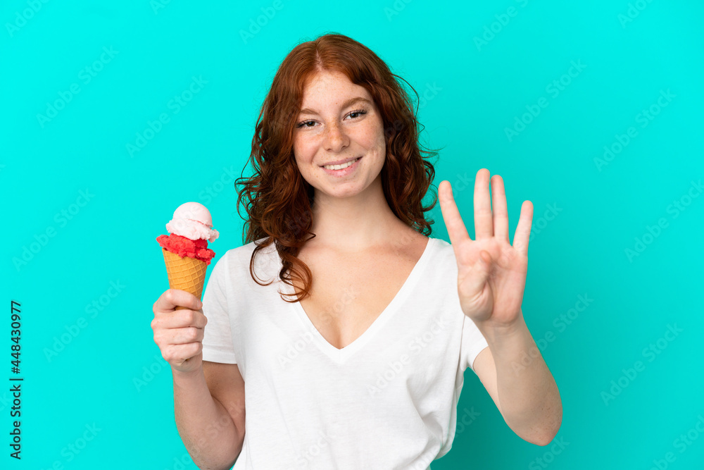 Teenager reddish woman with a cornet ice cream isolated on blue background happy and counting four with fingers Teenager reddish woman with a cornet ice cream isolated on blue background happy and counting four with fingers