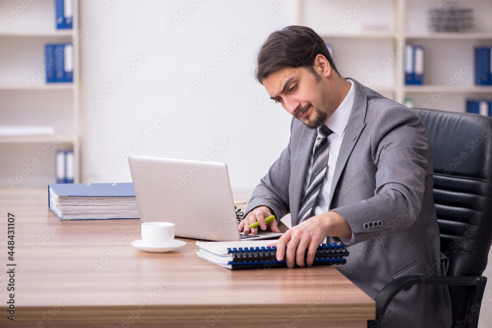 Young attractive male employee sitting at workplace Young attractive male employee sitting at workplace