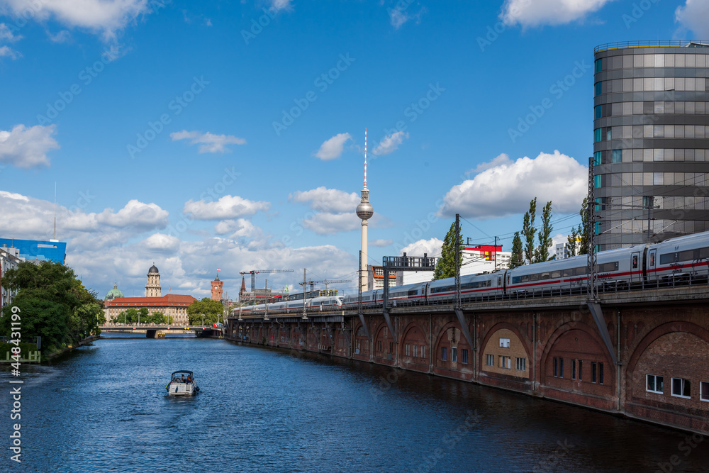 cityscape image of berlin with a view of the television tower, the spree river and a train on a railway bridge