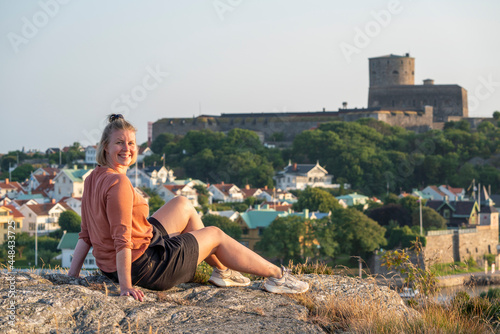 Smiling Caucasian Woman sunlit Enjoying Sunset over Swedish Summer party Island and Village Marstrand, Near Gothenburg and Sweden West Coast.