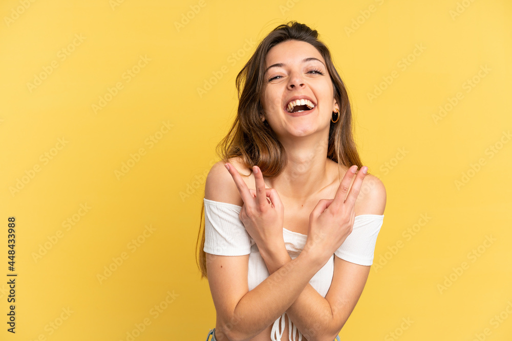 Young caucasian woman isolated on yellow background smiling and showing victory sign