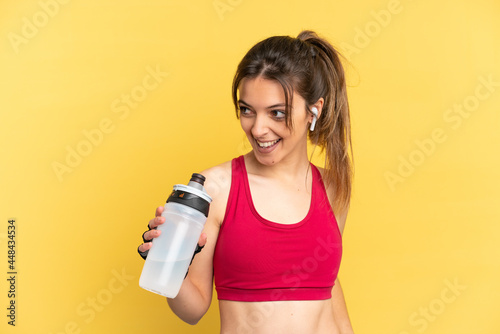 Young caucasian woman isolated on blue background with sports water bottle