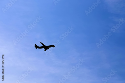 Airplane Silhouette against a blue sky. Bottom View of a commercial Airplane flying in the Sky..No logo or brand is visible. Copy space available.