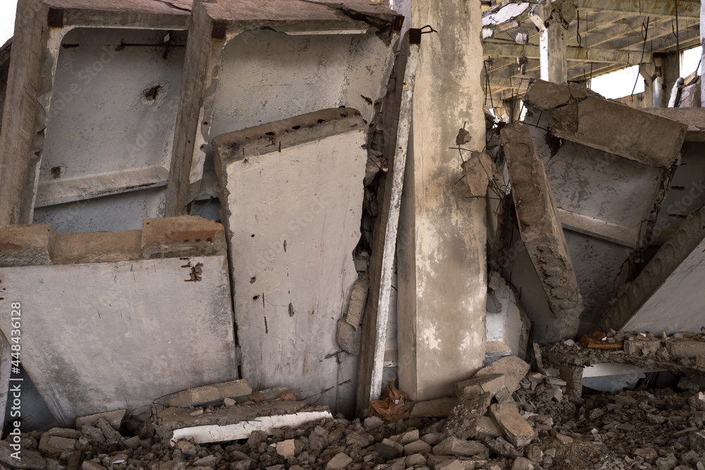 A pile of gray concrete slabs of the remains of the building in close-up against the background of the frame of the destroyed building. Background