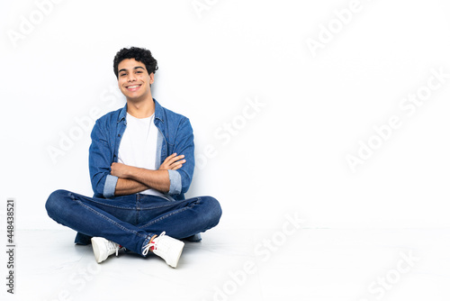 Venezuelan man sitting on the floor keeping the arms crossed in frontal position © luismolinero