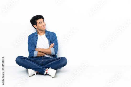 Venezuelan man sitting on the floor looking up while smiling © luismolinero