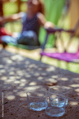 Fototapeta Naklejka Na Ścianę i Meble -  Transparent drinking glasses together at the edge of a table in an outdoor terrace restaurant scene