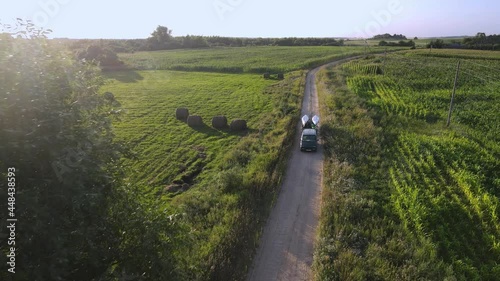 The green car with a trailer carries kayaks and canoes on a rural road. Aerial view. 4K.