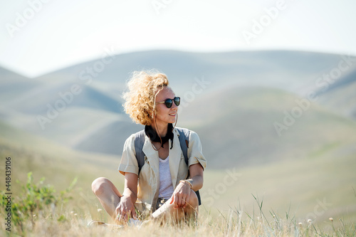 Valokuva Happy woman with curly messed up hair sitting amidst beautiful hills
