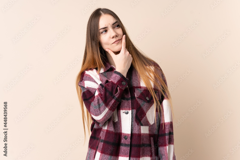 Young caucasian woman isolated on beige background having doubts