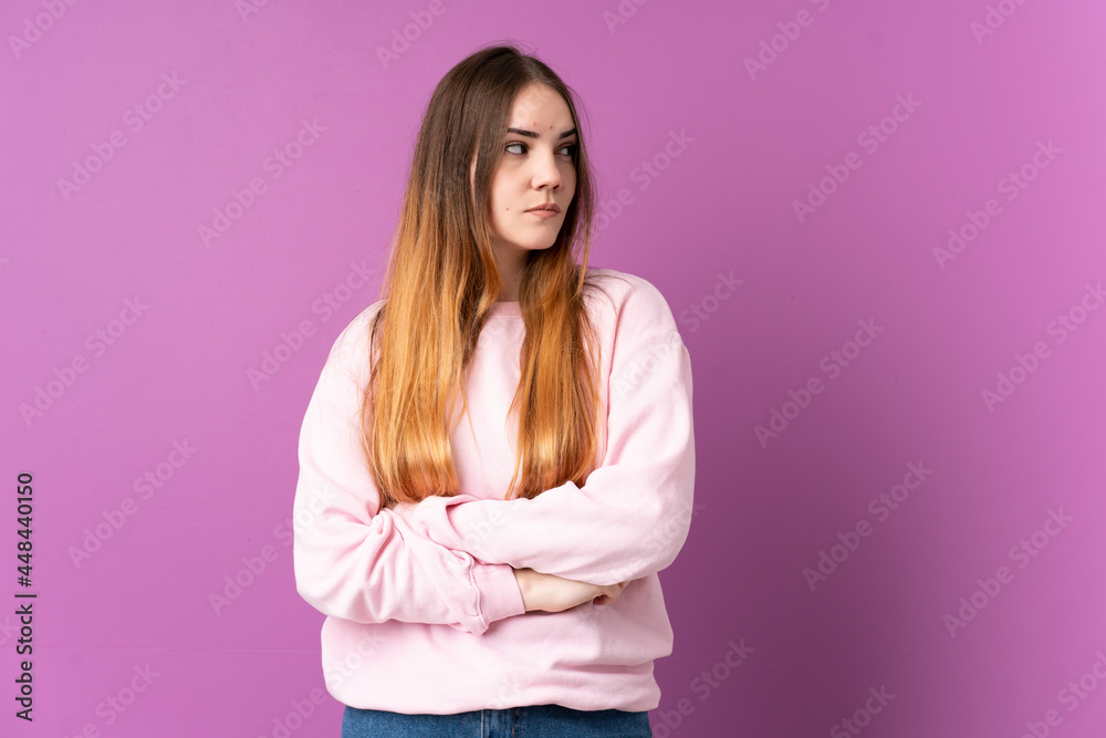 Young caucasian woman isolated on purple background looking to the side