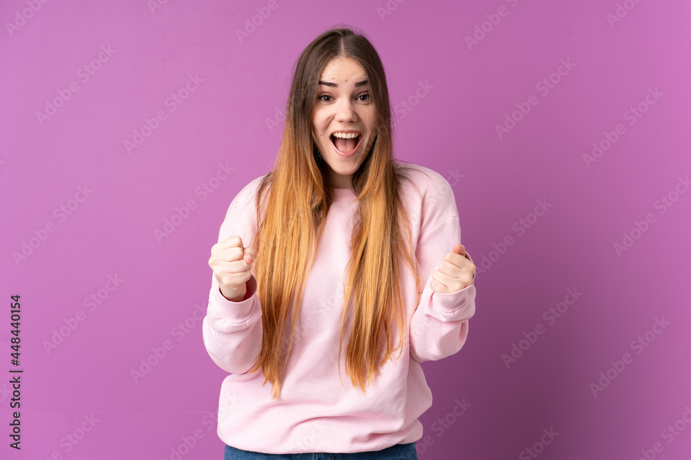 Young caucasian woman isolated on purple background celebrating a victory in winner position