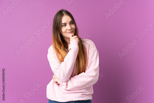 Young caucasian woman isolated on purple background and looking up