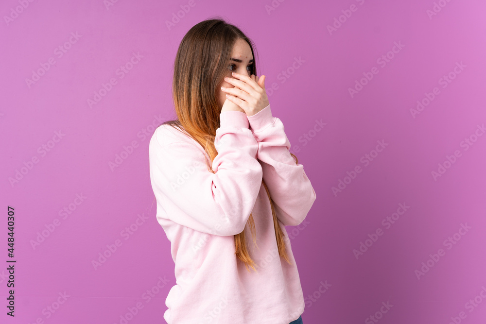 Young caucasian woman isolated on purple background covering mouth and looking to the side Young caucasian woman isolated on purple background covering mouth and looking to the side