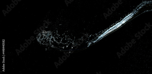 jet of transparent water with small drops and splashes on a black background
