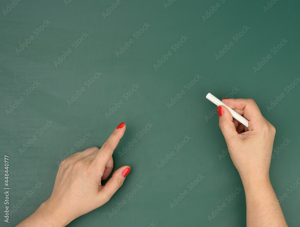 hand holds a piece of white chalk on the background of an empty green chalk board, presentation concept hand holds a piece of white chalk on the background of an empty green chalk board, presentation concept