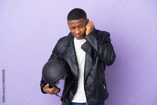 Latin man with a motorcycle helmet isolated on purple background frustrated and covering ears