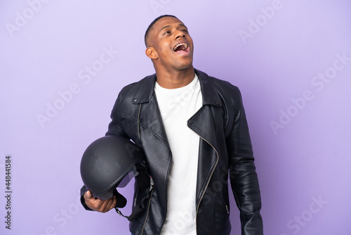 Latin man with a motorcycle helmet isolated on purple background laughing