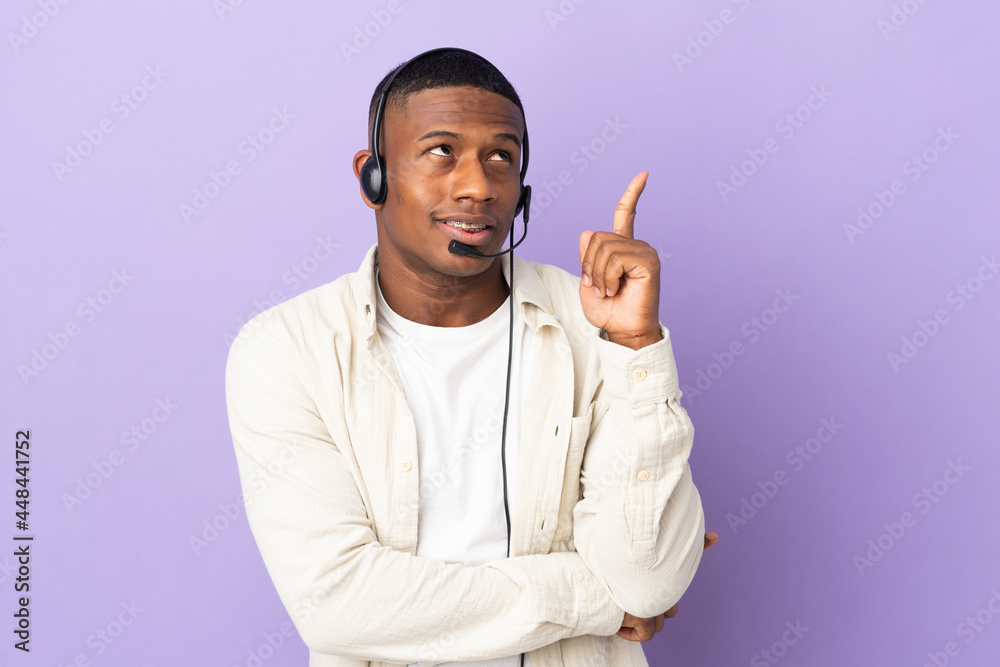 Telemarketer latin man working with a headset isolated on purple background pointing up a great idea Telemarketer latin man working with a headset isolated on purple background pointing up a great idea