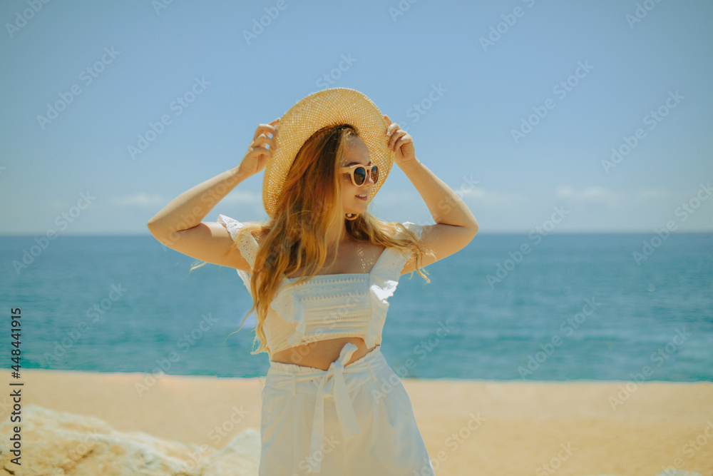 Beautiful girl on the background of the beach, sea and ocean. A blonde in a white outfit on vacation, wearing sunglasses and a larger hat, enjoying a vacation in the summer. Beautiful girl on the background of the beach, sea and ocean. A blonde in a white outfit on vacation, wearing sunglasses and a larger hat, enjoying a vacation in the summer.