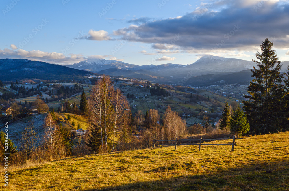 Late autumn mountain pre sunset scene with snow covered tops in far. Picturesque traveling, seasonal, nature and countryside beauty concept scene. Carpathians, Ukraine.