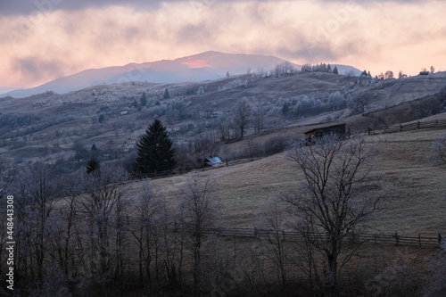 Winter coming. Last good weather days in autumn mountains countryside morning peaceful picturesque scene. Dirty road from hills to the village.