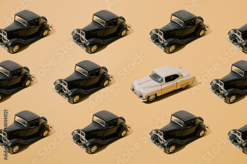 Plastic and metal old toy. Black retro car with beige limousine. Oldtimer on yellow gold luxury background. Pattern.