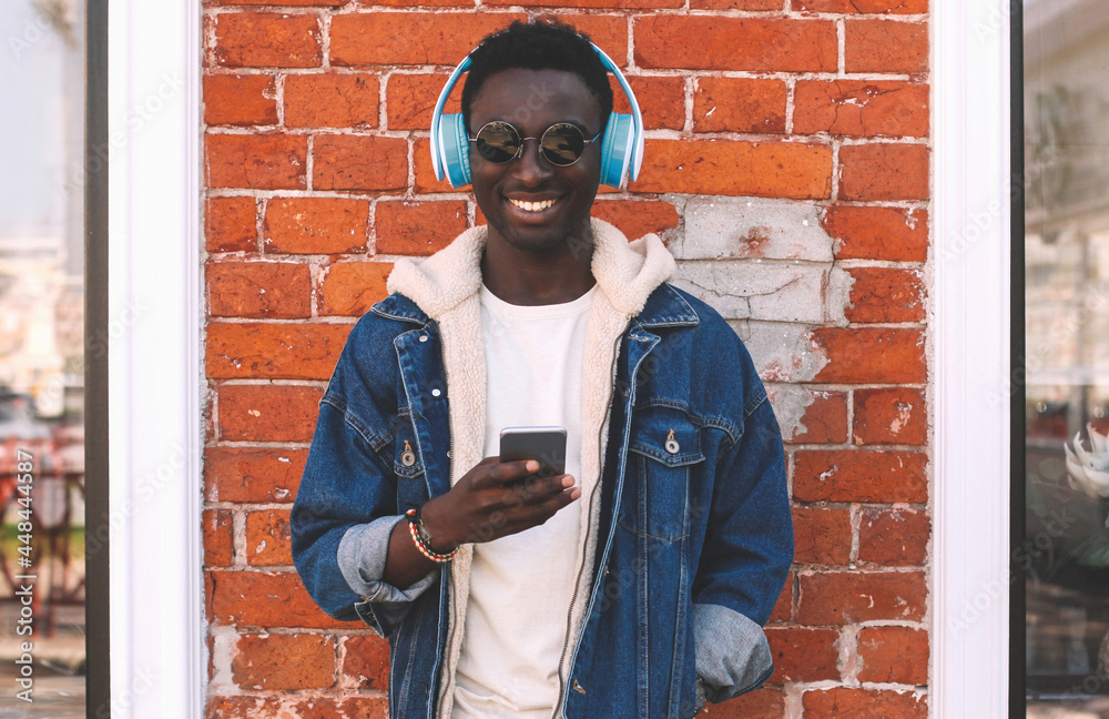 Portrait of happy smiling young african man with smartphone listening to music on city street Portrait of happy smiling young african man with smartphone listening to music on city street