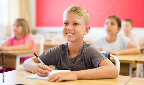 Small american school boy sitting at the desk in classroom at lesson in primary school