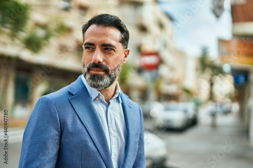 Middle age businessman with relaxed expression standing at the city.