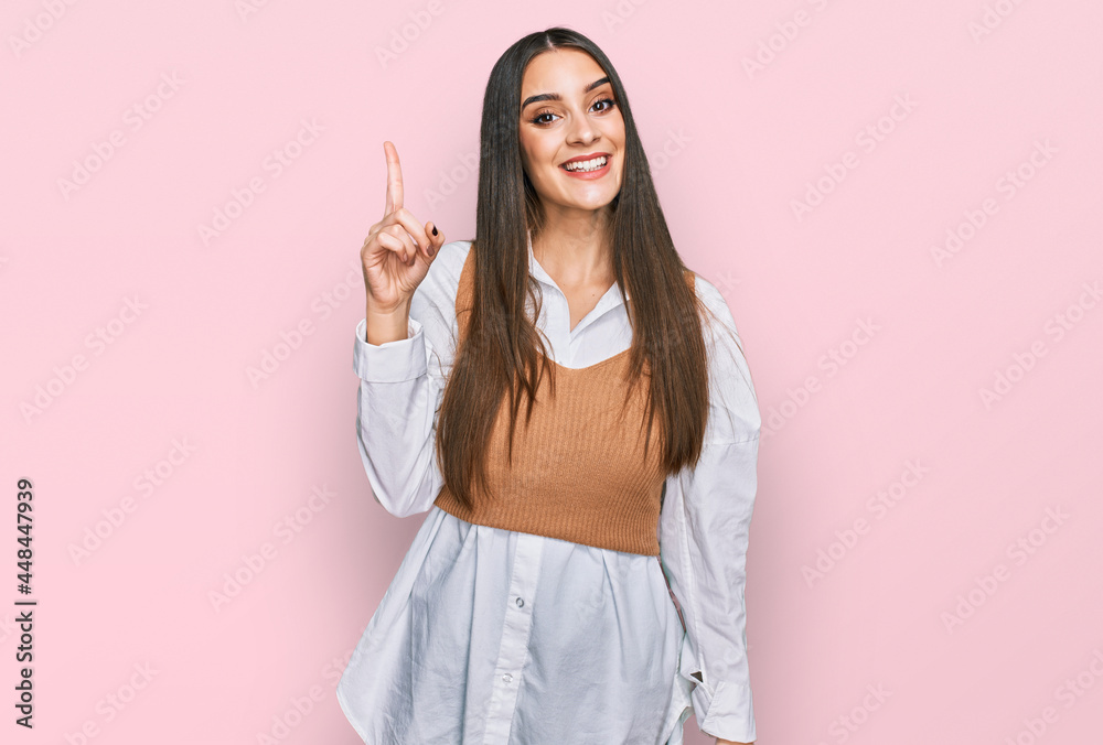 Young beautiful woman wearing casual white shirt pointing finger up with successful idea. exited and happy. number one. Young beautiful woman wearing casual white shirt pointing finger up with successful idea. exited and happy. number one.