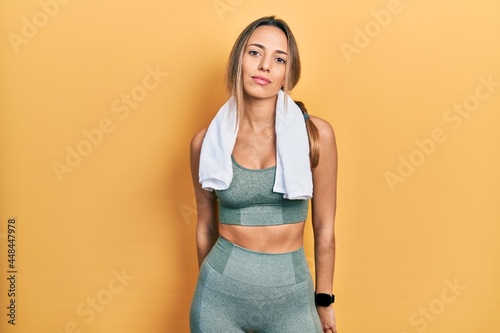 Beautiful hispanic woman wearing sportswear and towel relaxed with serious expression on face. simple and natural looking at the camera. © Krakenimages.com