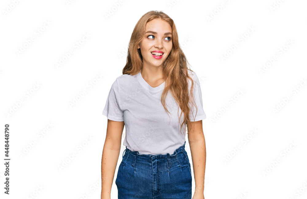 Obraz premium Young caucasian girl wearing casual white t shirt looking away to side with smile on face, natural expression. laughing confident.