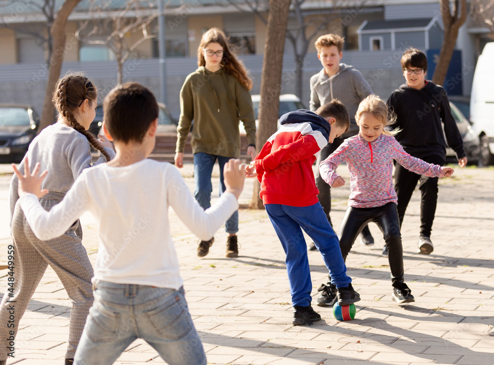 Group of children playing soccer with ball outdoors and having fun