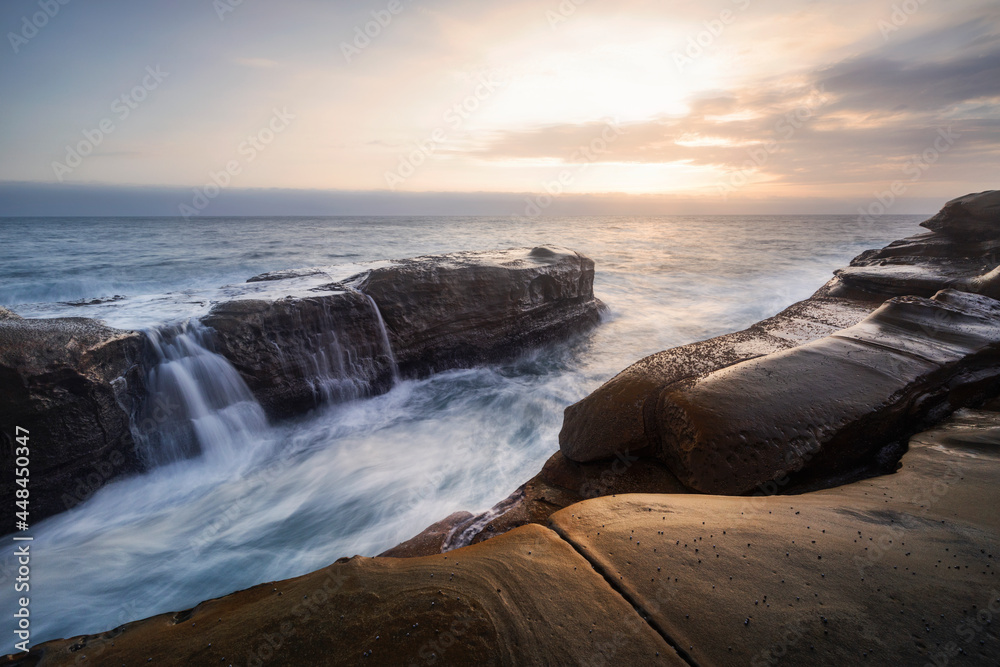 sunrise on the rocks at the coast with a waterfall