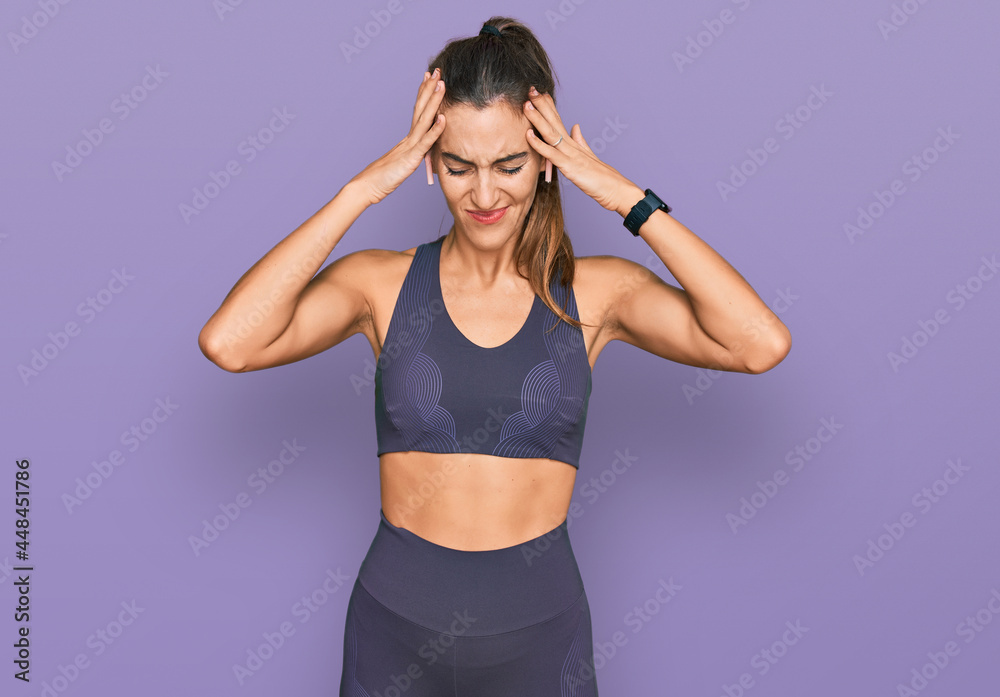 Young beautiful woman wearing sportswear suffering from headache desperate and stressed because pain and migraine. hands on head.