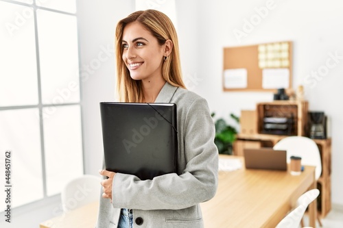 Young caucasian businesswoman smiling happy holding folder at the office.